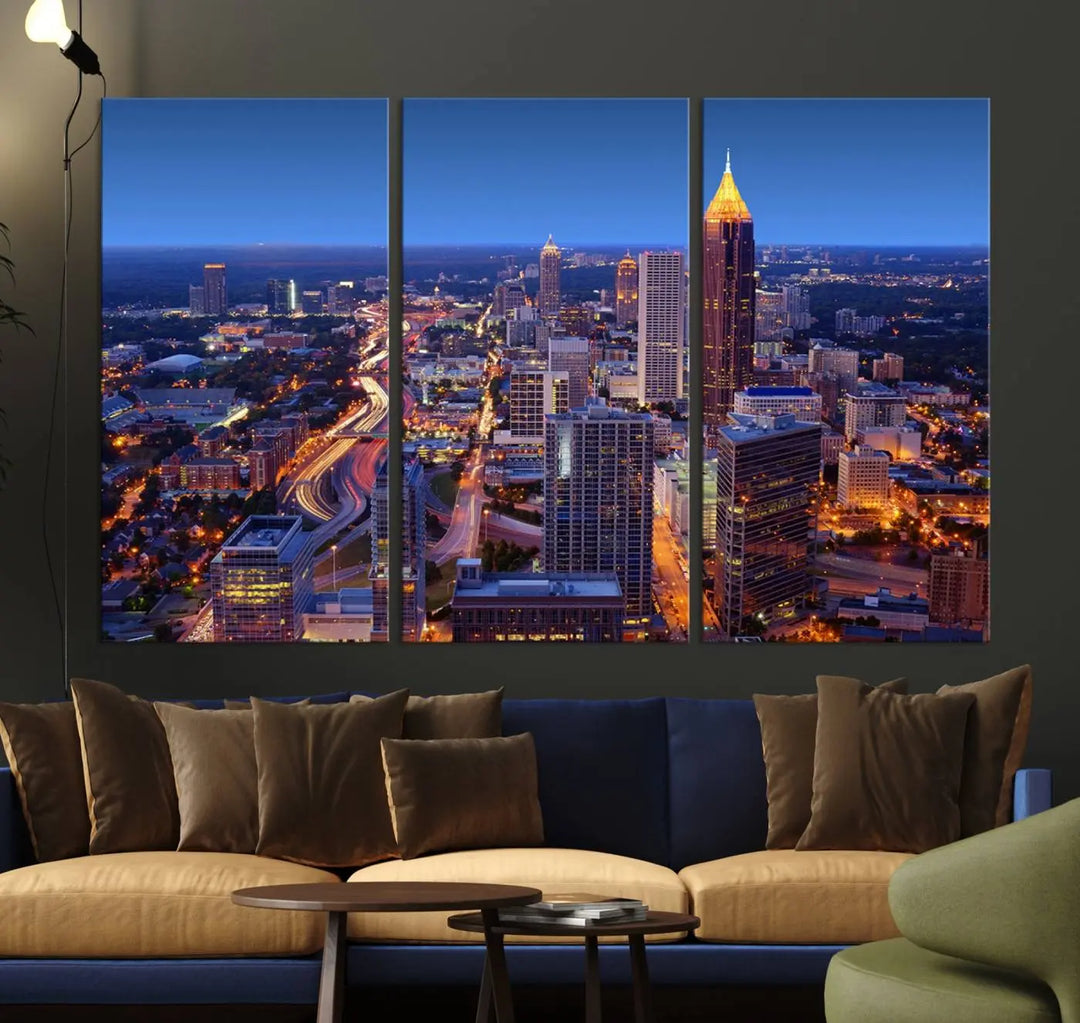 The triptych titled "Atlanta Wall Art Canvas Print" decorates the wall in a modern living room. This museum-quality artwork of a cityscape at night is ready to hang and features a UV-protective coating that ensures lasting vibrancy and elegance.