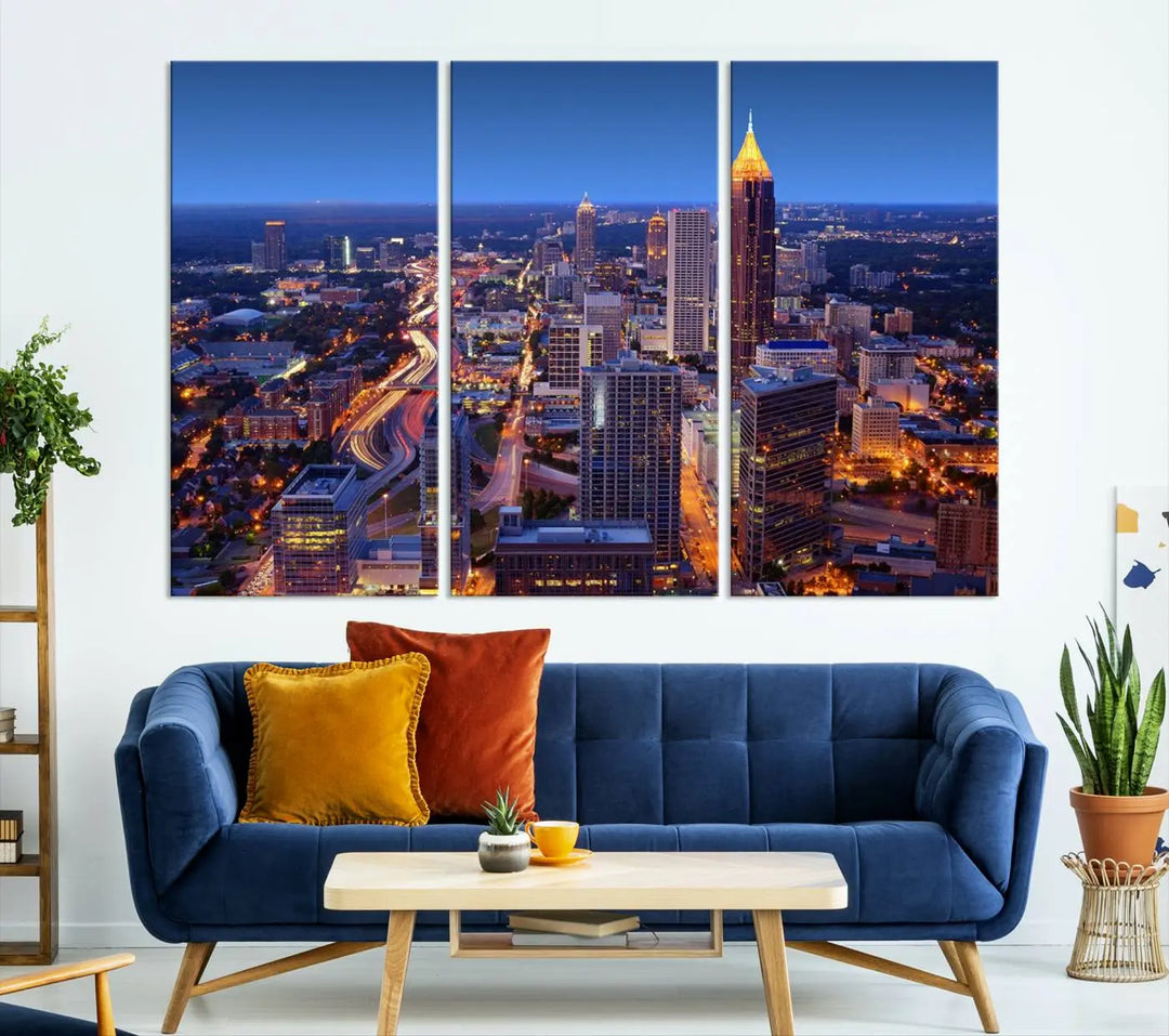 The triptych titled "Atlanta Wall Art Canvas Print" decorates the wall in a modern living room. This museum-quality artwork of a cityscape at night is ready to hang and features a UV-protective coating that ensures lasting vibrancy and elegance.