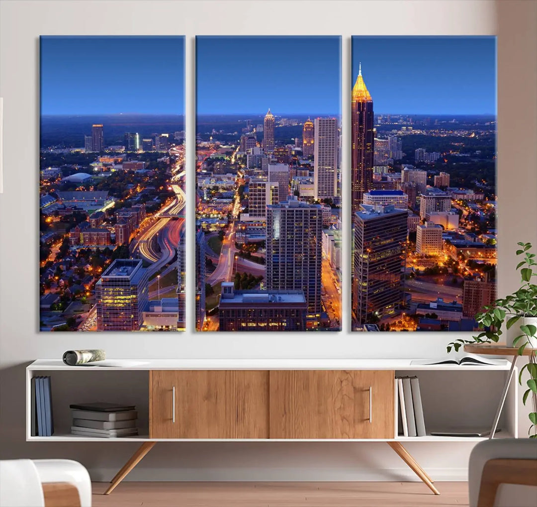 The triptych titled "Atlanta Wall Art Canvas Print" decorates the wall in a modern living room. This museum-quality artwork of a cityscape at night is ready to hang and features a UV-protective coating that ensures lasting vibrancy and elegance.