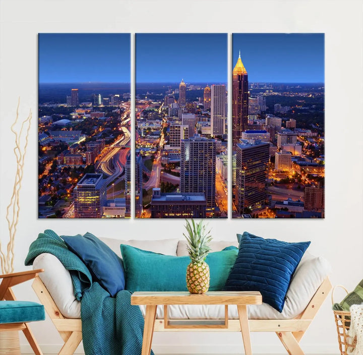 The triptych titled "Atlanta Wall Art Canvas Print" decorates the wall in a modern living room. This museum-quality artwork of a cityscape at night is ready to hang and features a UV-protective coating that ensures lasting vibrancy and elegance.