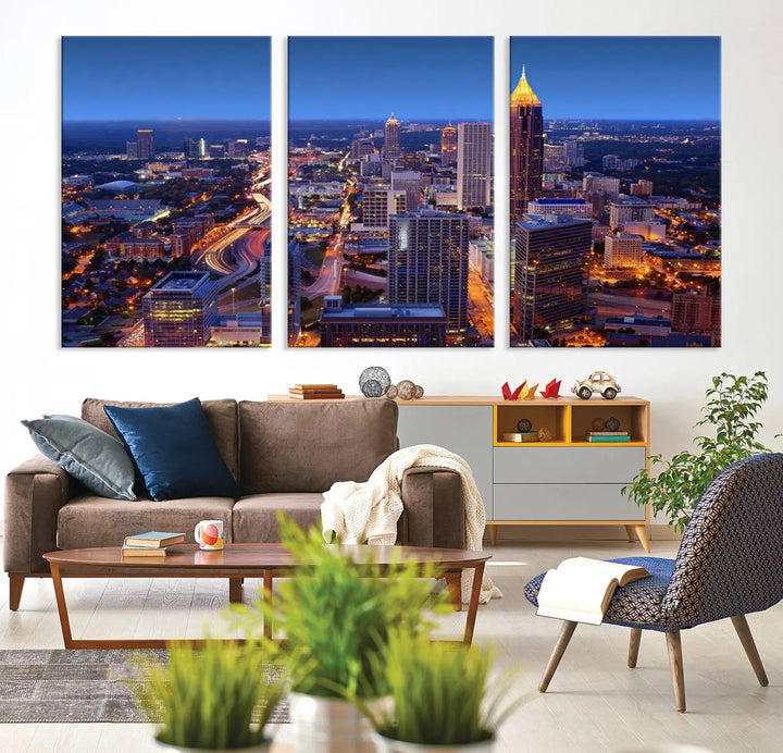 The triptych titled "Atlanta Wall Art Canvas Print" decorates the wall in a modern living room. This museum-quality artwork of a cityscape at night is ready to hang and features a UV-protective coating that ensures lasting vibrancy and elegance.