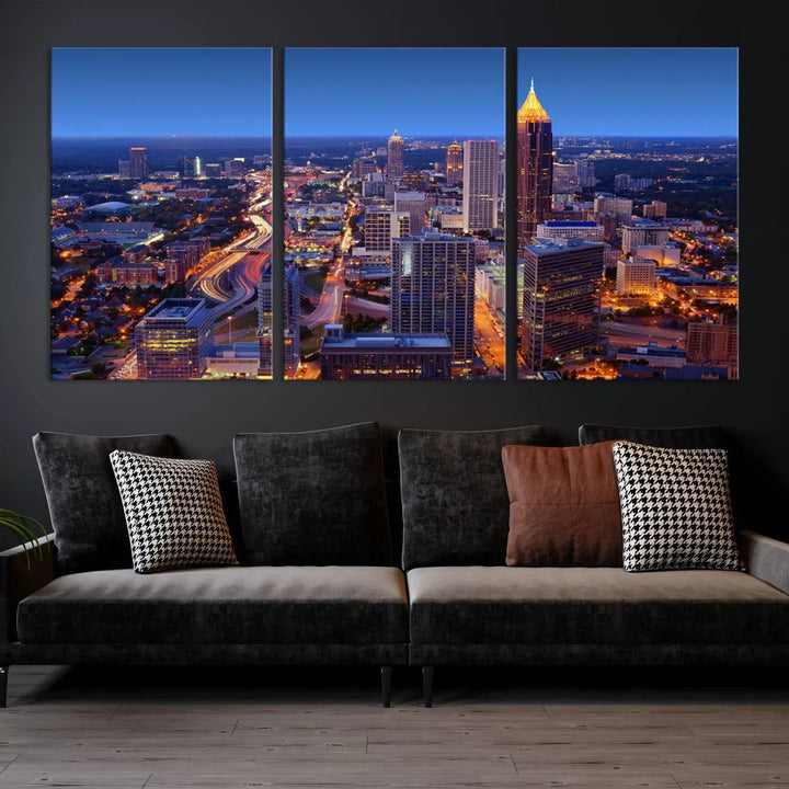 The triptych titled "Atlanta Wall Art Canvas Print" decorates the wall in a modern living room. This museum-quality artwork of a cityscape at night is ready to hang and features a UV-protective coating that ensures lasting vibrancy and elegance.