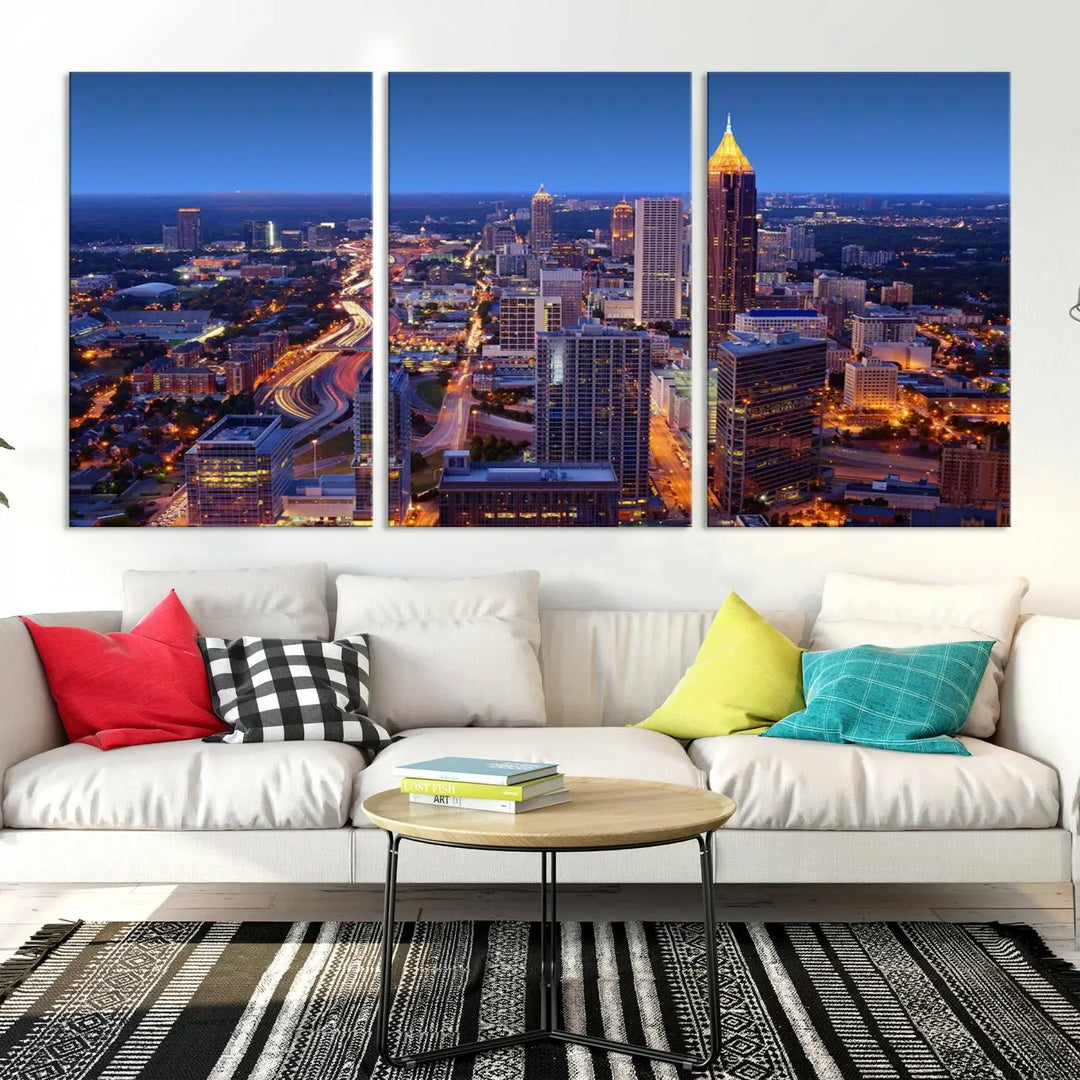 The triptych titled "Atlanta Wall Art Canvas Print" decorates the wall in a modern living room. This museum-quality artwork of a cityscape at night is ready to hang and features a UV-protective coating that ensures lasting vibrancy and elegance.