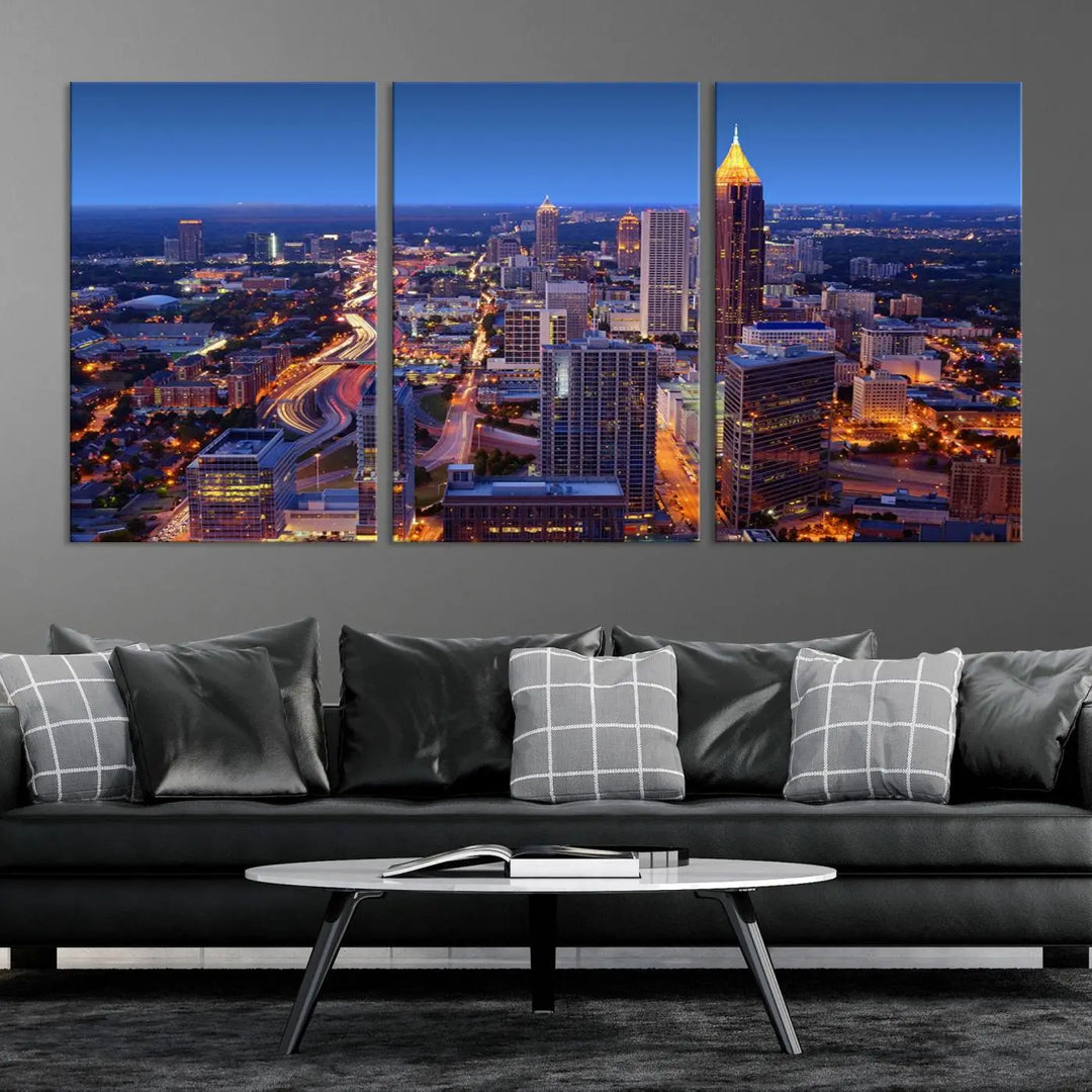 The triptych titled "Atlanta Wall Art Canvas Print" decorates the wall in a modern living room. This museum-quality artwork of a cityscape at night is ready to hang and features a UV-protective coating that ensures lasting vibrancy and elegance.