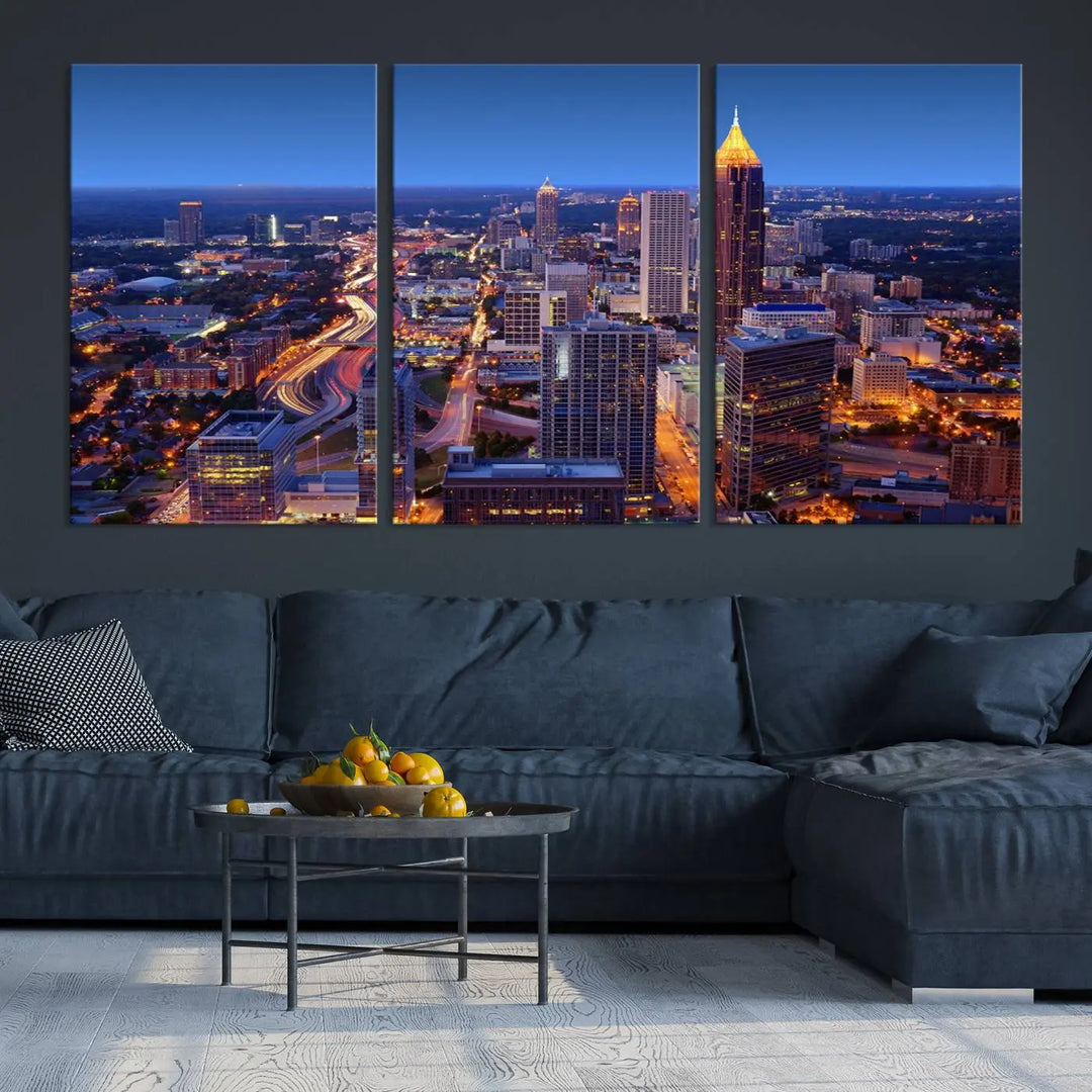 The triptych titled "Atlanta Wall Art Canvas Print" decorates the wall in a modern living room. This museum-quality artwork of a cityscape at night is ready to hang and features a UV-protective coating that ensures lasting vibrancy and elegance.