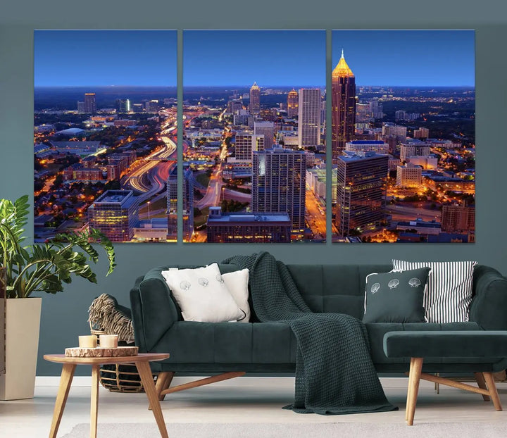 The triptych titled "Atlanta Wall Art Canvas Print" decorates the wall in a modern living room. This museum-quality artwork of a cityscape at night is ready to hang and features a UV-protective coating that ensures lasting vibrancy and elegance.