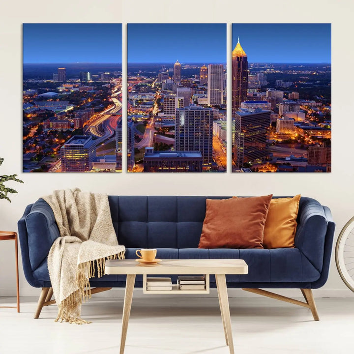 The triptych titled "Atlanta Wall Art Canvas Print" decorates the wall in a modern living room. This museum-quality artwork of a cityscape at night is ready to hang and features a UV-protective coating that ensures lasting vibrancy and elegance.