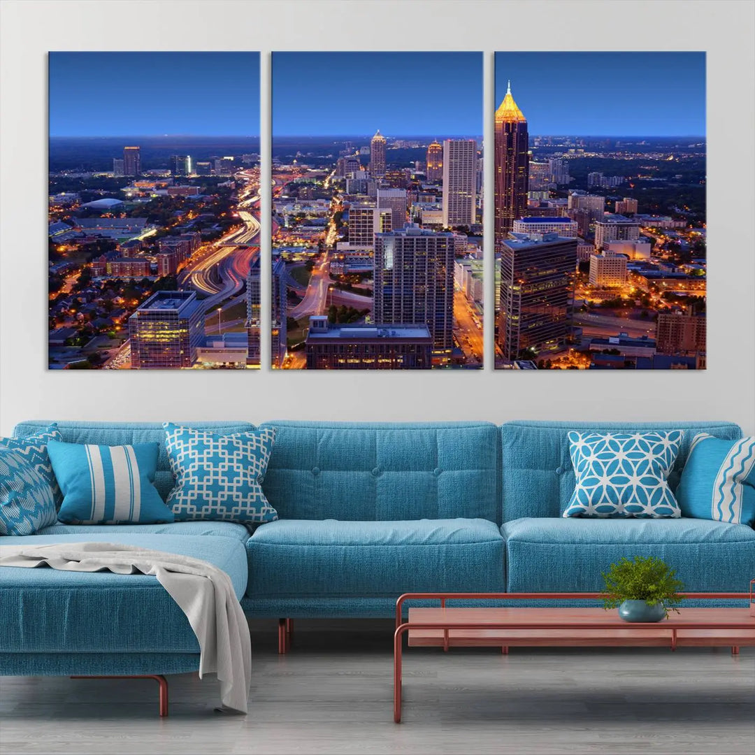 The triptych titled "Atlanta Wall Art Canvas Print" decorates the wall in a modern living room. This museum-quality artwork of a cityscape at night is ready to hang and features a UV-protective coating that ensures lasting vibrancy and elegance.