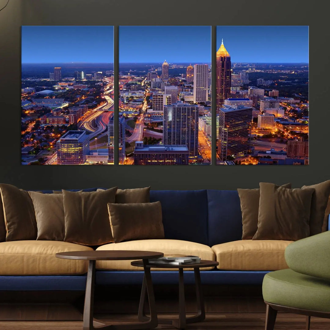 The triptych titled "Atlanta Wall Art Canvas Print" decorates the wall in a modern living room. This museum-quality artwork of a cityscape at night is ready to hang and features a UV-protective coating that ensures lasting vibrancy and elegance.