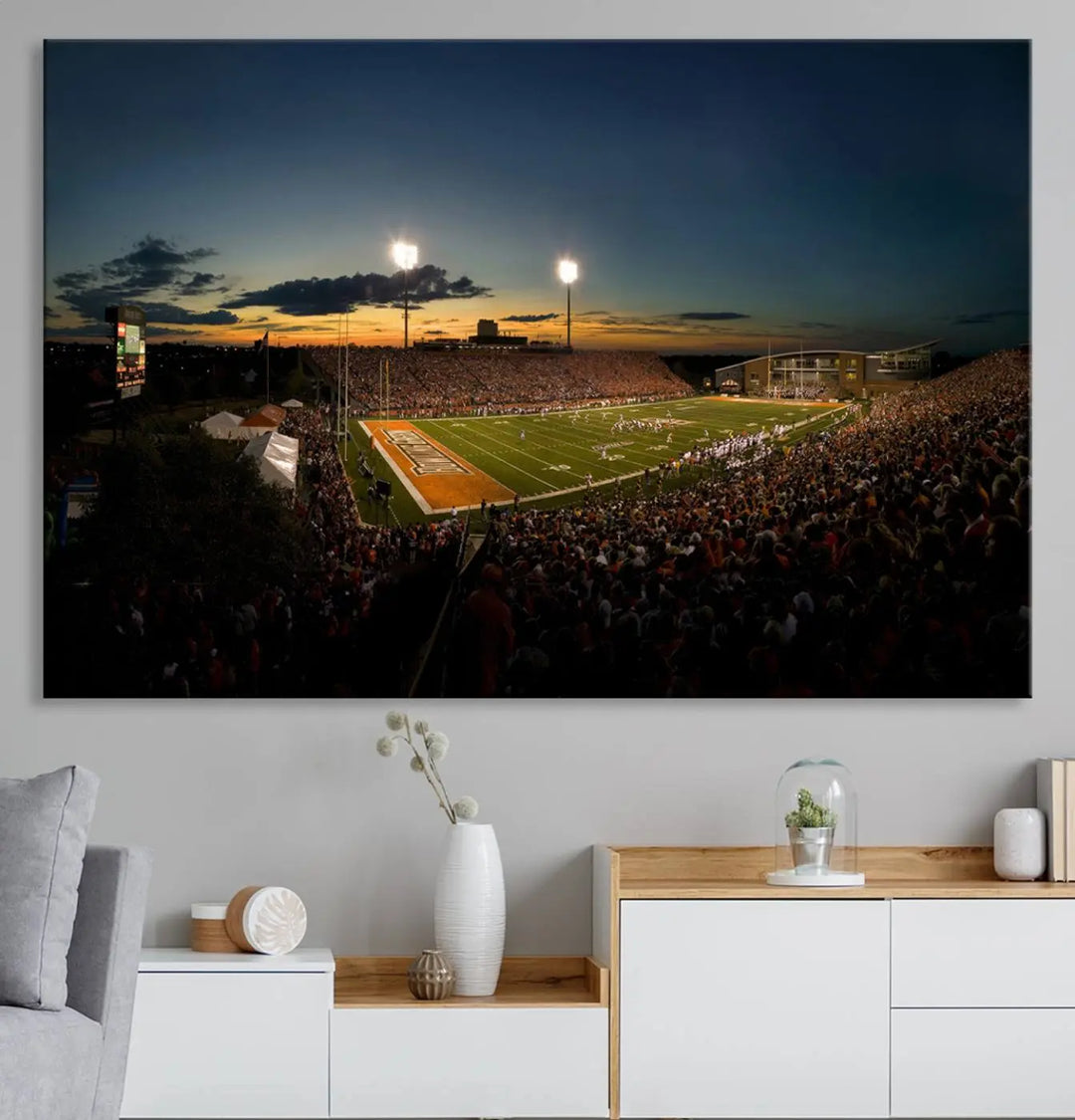 Experience the vibrant energy of game day with the Ball State Cardinals Football Team Print - Muncie Scheumann Stadium Wall Art Canvas Print. This stunning artwork captures a sunset-lit football stadium, alive with a match in progress and spectators filling the stands under floodlights, all rendered on museum-quality canvas.