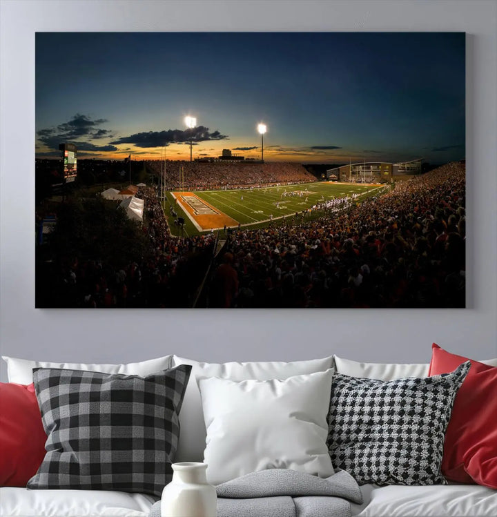 Experience the vibrant energy of game day with the Ball State Cardinals Football Team Print - Muncie Scheumann Stadium Wall Art Canvas Print. This stunning artwork captures a sunset-lit football stadium, alive with a match in progress and spectators filling the stands under floodlights, all rendered on museum-quality canvas.