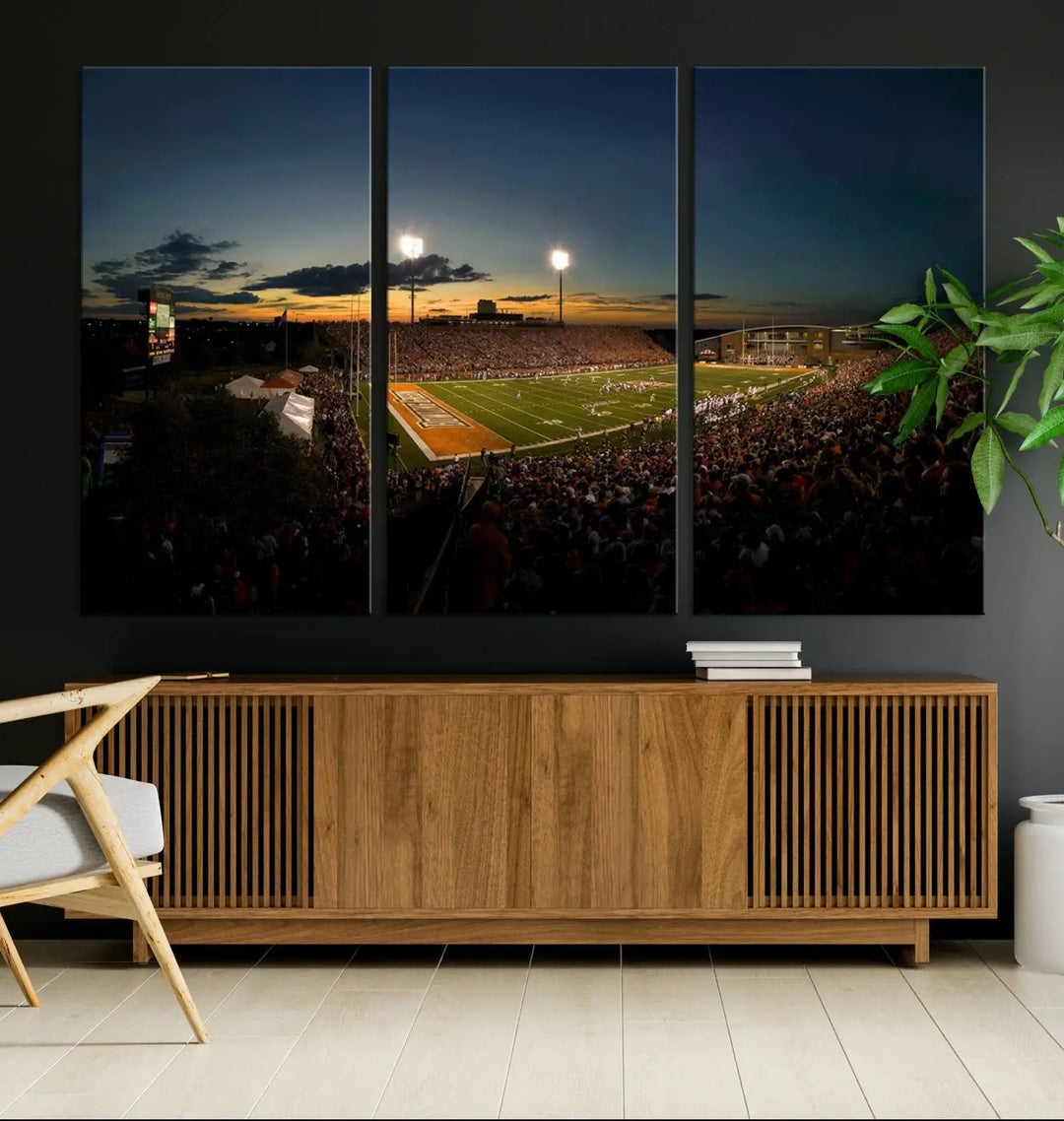 Experience the vibrant energy of game day with the Ball State Cardinals Football Team Print - Muncie Scheumann Stadium Wall Art Canvas Print. This stunning artwork captures a sunset-lit football stadium, alive with a match in progress and spectators filling the stands under floodlights, all rendered on museum-quality canvas.