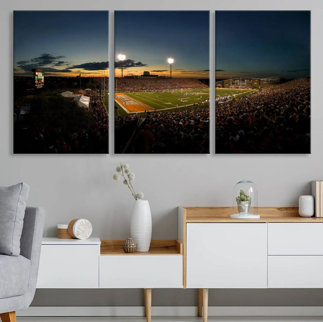 Experience the vibrant energy of game day with the Ball State Cardinals Football Team Print - Muncie Scheumann Stadium Wall Art Canvas Print. This stunning artwork captures a sunset-lit football stadium, alive with a match in progress and spectators filling the stands under floodlights, all rendered on museum-quality canvas.