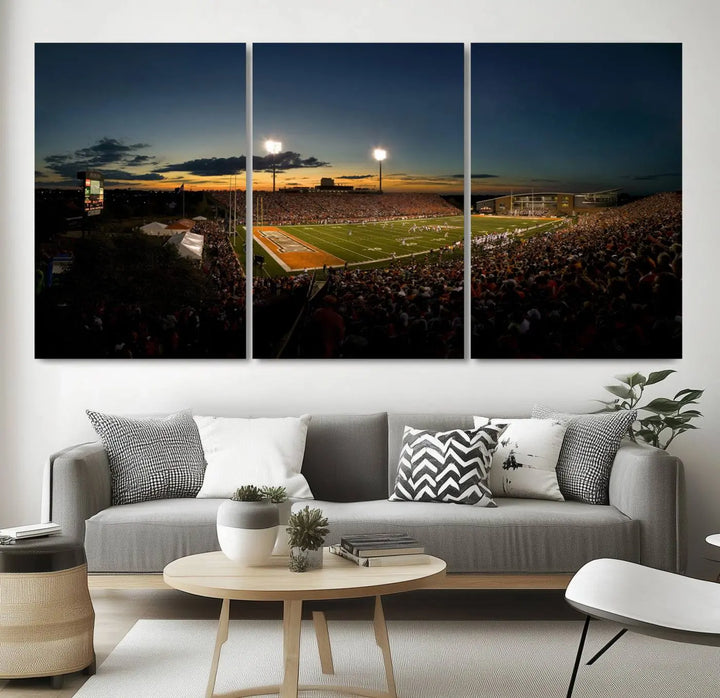 Experience the vibrant energy of game day with the Ball State Cardinals Football Team Print - Muncie Scheumann Stadium Wall Art Canvas Print. This stunning artwork captures a sunset-lit football stadium, alive with a match in progress and spectators filling the stands under floodlights, all rendered on museum-quality canvas.