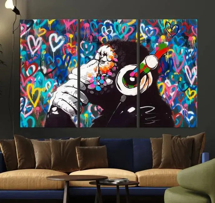 A triptych featuring the "Banksy Canvas Wall Art Thinking Monkey Canvas Art Print" showcases a chimp wearing headphones against a colorful heart-patterned background. Each museum-quality canvas is gallery wrapped and finished with a UV-protective coating to ensure lasting brilliance.