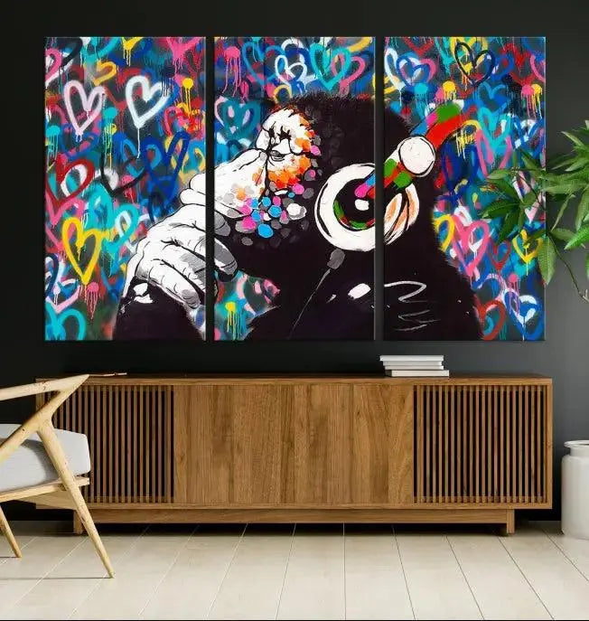 A triptych featuring the "Banksy Canvas Wall Art Thinking Monkey Canvas Art Print" showcases a chimp wearing headphones against a colorful heart-patterned background. Each museum-quality canvas is gallery wrapped and finished with a UV-protective coating to ensure lasting brilliance.