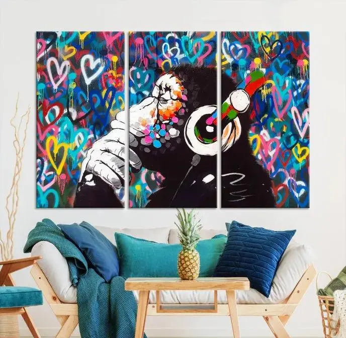 A triptych featuring the "Banksy Canvas Wall Art Thinking Monkey Canvas Art Print" showcases a chimp wearing headphones against a colorful heart-patterned background. Each museum-quality canvas is gallery wrapped and finished with a UV-protective coating to ensure lasting brilliance.