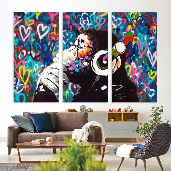 A triptych featuring the "Banksy Canvas Wall Art Thinking Monkey Canvas Art Print" showcases a chimp wearing headphones against a colorful heart-patterned background. Each museum-quality canvas is gallery wrapped and finished with a UV-protective coating to ensure lasting brilliance.