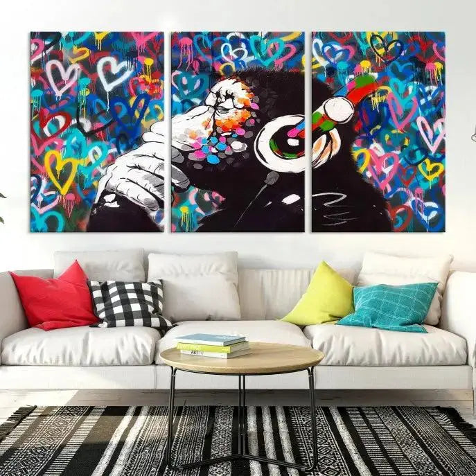 A triptych featuring the "Banksy Canvas Wall Art Thinking Monkey Canvas Art Print" showcases a chimp wearing headphones against a colorful heart-patterned background. Each museum-quality canvas is gallery wrapped and finished with a UV-protective coating to ensure lasting brilliance.