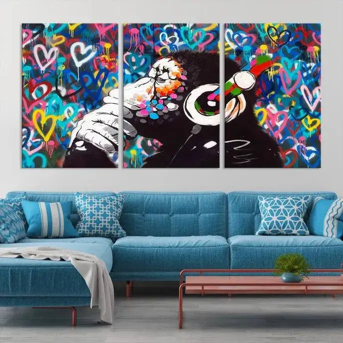 A triptych featuring the "Banksy Canvas Wall Art Thinking Monkey Canvas Art Print" showcases a chimp wearing headphones against a colorful heart-patterned background. Each museum-quality canvas is gallery wrapped and finished with a UV-protective coating to ensure lasting brilliance.