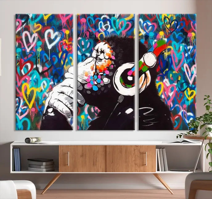 A triptych featuring the "Banksy Canvas Wall Art Thinking Monkey Canvas Art Print" showcases a chimp wearing headphones against a colorful heart-patterned background. Each museum-quality canvas is gallery wrapped and finished with a UV-protective coating to ensure lasting brilliance.