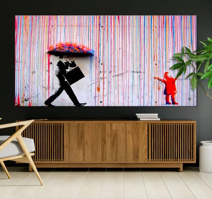 Introducing the Banksy Street Art Wall Art Canvas Print, a captivating piece featuring modern art of a man with an umbrella while a child reaches up through vibrant drips. Its premium canvas and gallery-quality finish make it an eye-catching addition to any space.