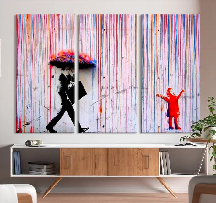 Introducing the Banksy Street Art Wall Art Canvas Print, a captivating piece featuring modern art of a man with an umbrella while a child reaches up through vibrant drips. Its premium canvas and gallery-quality finish make it an eye-catching addition to any space.