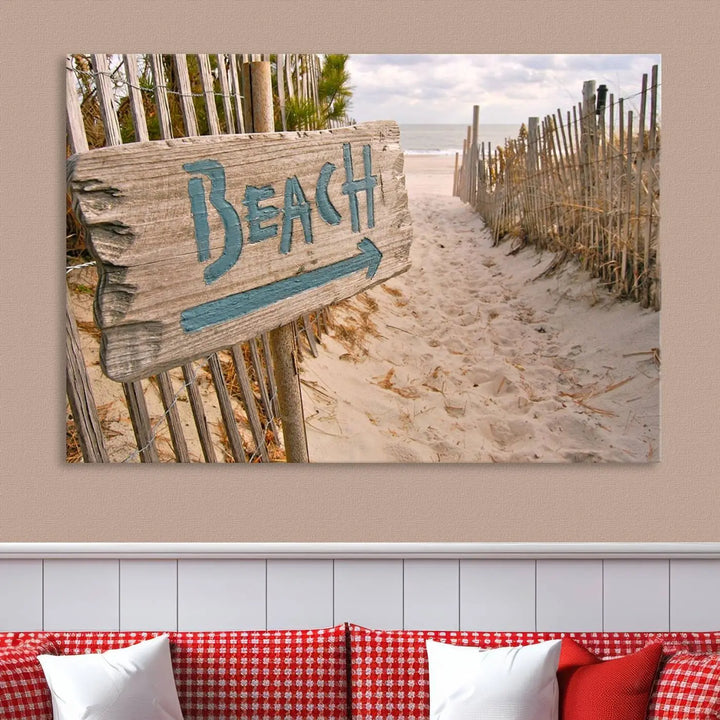 The Beach Is Calling You Wall Art Canvas Print features a sandy beach path with a wooden beach sign and arrow pointing to the ocean, beautifully displayed on museum-quality canvases.