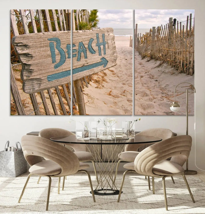 The Beach Is Calling You Wall Art Canvas Print features a sandy beach path with a wooden beach sign and arrow pointing to the ocean, beautifully displayed on museum-quality canvases.