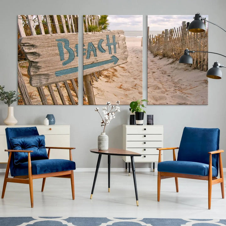 The Beach Is Calling You Wall Art Canvas Print features a sandy beach path with a wooden beach sign and arrow pointing to the ocean, beautifully displayed on museum-quality canvases.