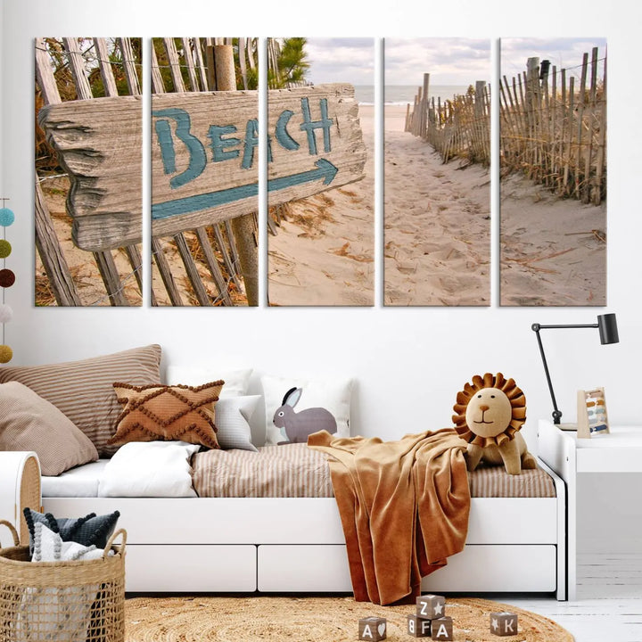 The Beach Is Calling You Wall Art Canvas Print features a sandy beach path with a wooden beach sign and arrow pointing to the ocean, beautifully displayed on museum-quality canvases.