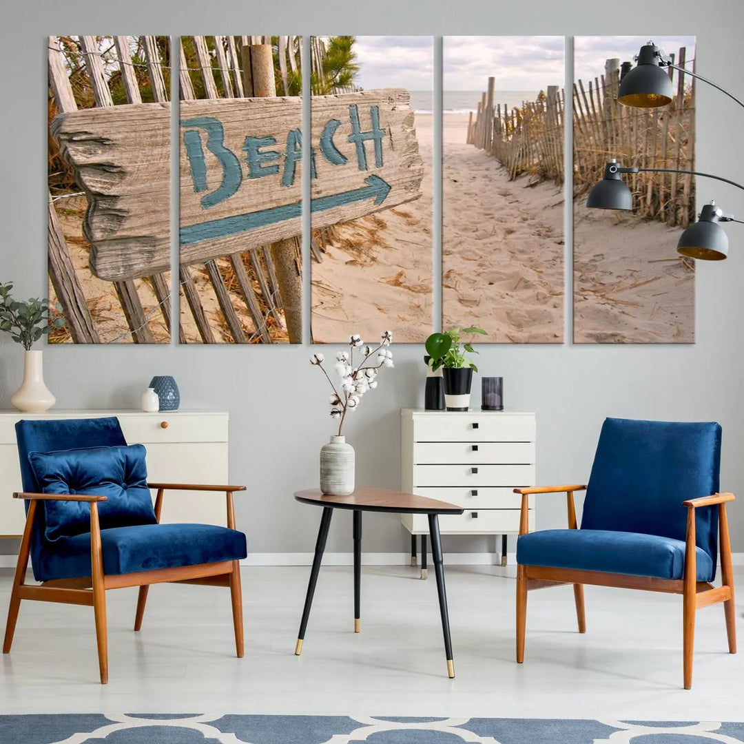 The Beach Is Calling You Wall Art Canvas Print features a sandy beach path with a wooden beach sign and arrow pointing to the ocean, beautifully displayed on museum-quality canvases.