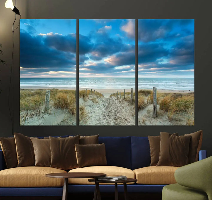 The "Beach Ocean Sun Sand Wall Art Canvas Print" is a triptych showcasing a beach path with grass leading to the ocean under a dramatic cloudy sky. This museum-quality canvas includes a UV-protective coating for longevity and vibrancy, and it comes ready to hang for effortless elegance.