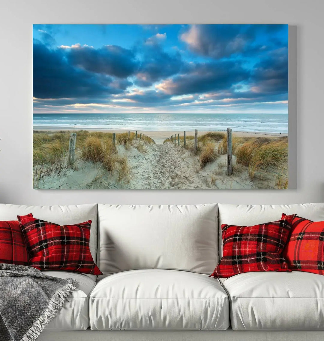 The "Beach Ocean Sun Sand Wall Art Canvas Print" is a triptych showcasing a beach path with grass leading to the ocean under a dramatic cloudy sky. This museum-quality canvas includes a UV-protective coating for longevity and vibrancy, and it comes ready to hang for effortless elegance.