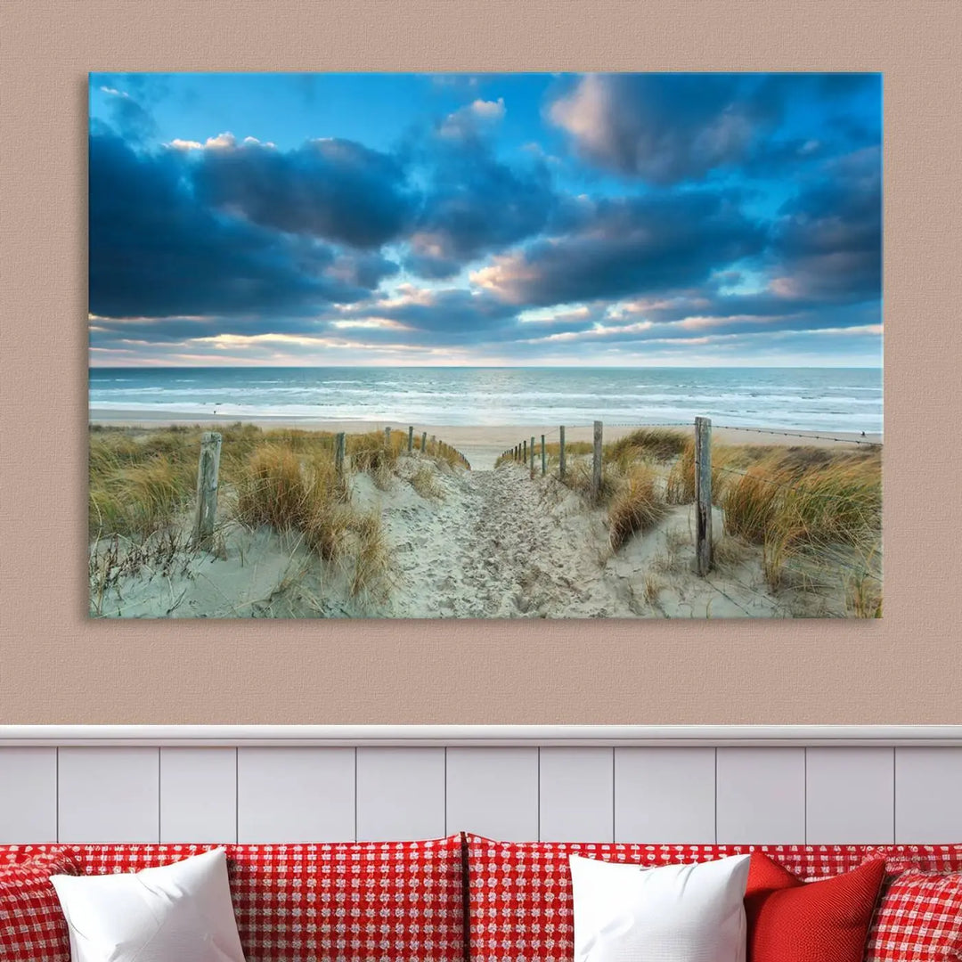 The "Beach Ocean Sun Sand Wall Art Canvas Print" is a triptych showcasing a beach path with grass leading to the ocean under a dramatic cloudy sky. This museum-quality canvas includes a UV-protective coating for longevity and vibrancy, and it comes ready to hang for effortless elegance.