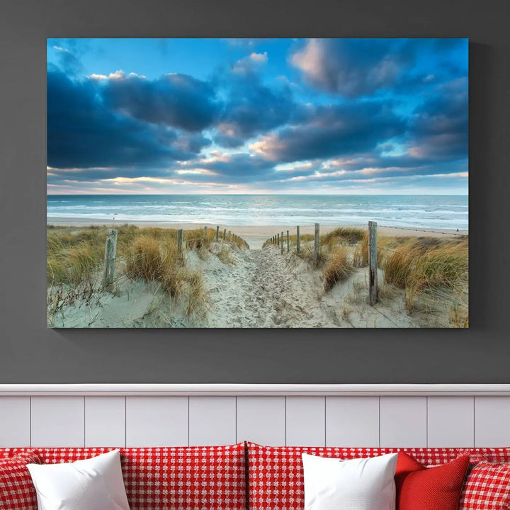 The "Beach Ocean Sun Sand Wall Art Canvas Print" is a triptych showcasing a beach path with grass leading to the ocean under a dramatic cloudy sky. This museum-quality canvas includes a UV-protective coating for longevity and vibrancy, and it comes ready to hang for effortless elegance.