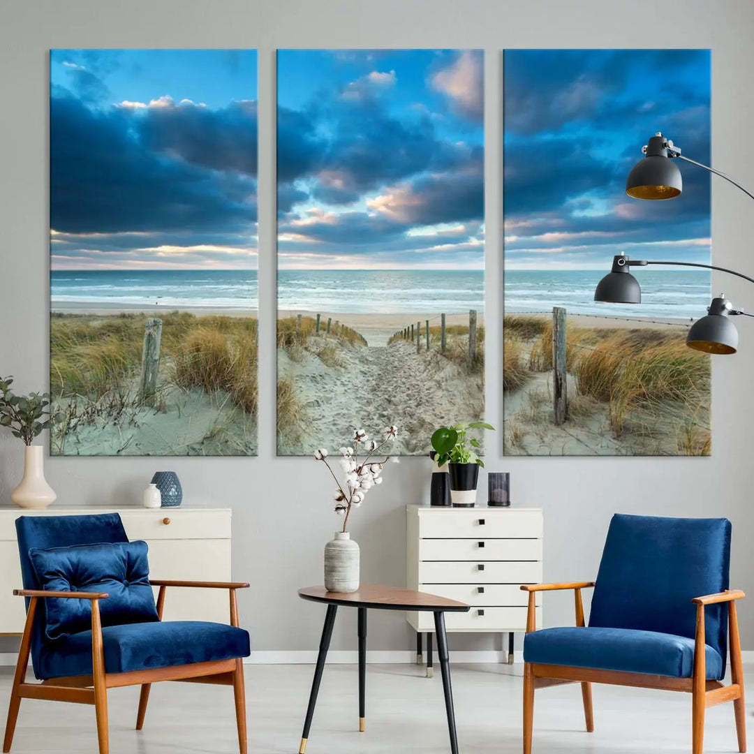 The "Beach Ocean Sun Sand Wall Art Canvas Print" is a triptych showcasing a beach path with grass leading to the ocean under a dramatic cloudy sky. This museum-quality canvas includes a UV-protective coating for longevity and vibrancy, and it comes ready to hang for effortless elegance.