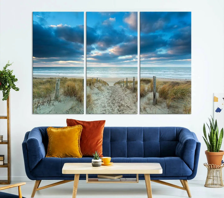 The "Beach Ocean Sun Sand Wall Art Canvas Print" is a triptych showcasing a beach path with grass leading to the ocean under a dramatic cloudy sky. This museum-quality canvas includes a UV-protective coating for longevity and vibrancy, and it comes ready to hang for effortless elegance.