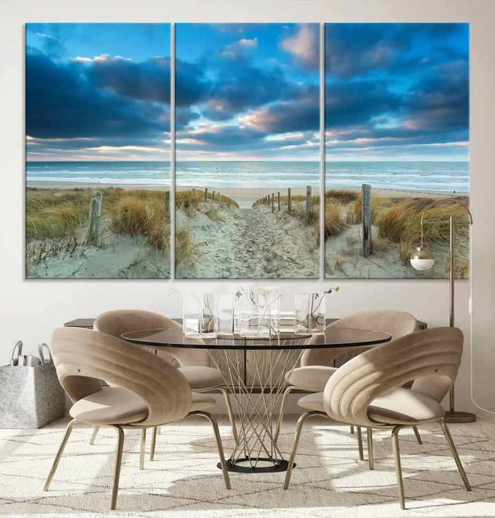 The "Beach Ocean Sun Sand Wall Art Canvas Print" is a triptych showcasing a beach path with grass leading to the ocean under a dramatic cloudy sky. This museum-quality canvas includes a UV-protective coating for longevity and vibrancy, and it comes ready to hang for effortless elegance.