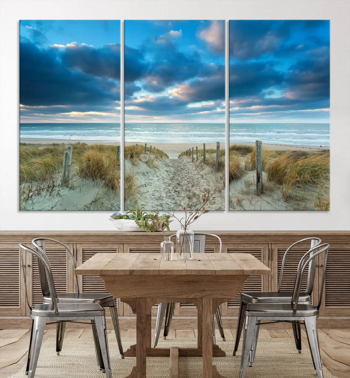 The "Beach Ocean Sun Sand Wall Art Canvas Print" is a triptych showcasing a beach path with grass leading to the ocean under a dramatic cloudy sky. This museum-quality canvas includes a UV-protective coating for longevity and vibrancy, and it comes ready to hang for effortless elegance.