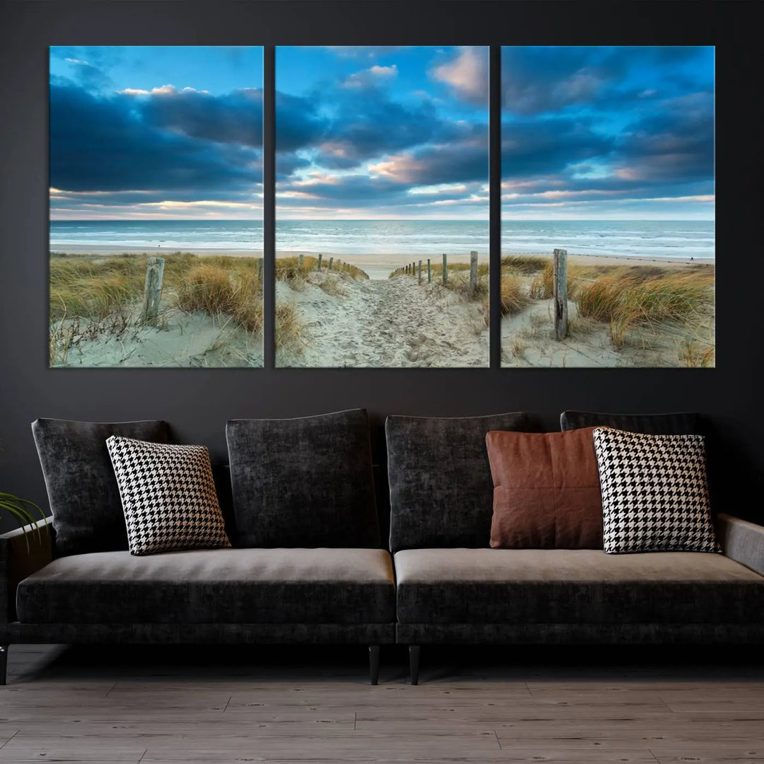 The "Beach Ocean Sun Sand Wall Art Canvas Print" is a triptych showcasing a beach path with grass leading to the ocean under a dramatic cloudy sky. This museum-quality canvas includes a UV-protective coating for longevity and vibrancy, and it comes ready to hang for effortless elegance.