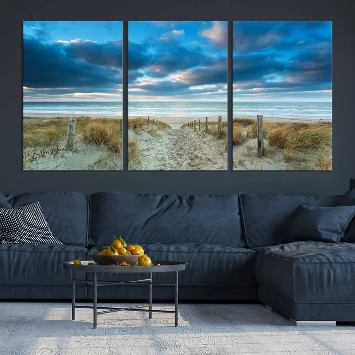 The "Beach Ocean Sun Sand Wall Art Canvas Print" is a triptych showcasing a beach path with grass leading to the ocean under a dramatic cloudy sky. This museum-quality canvas includes a UV-protective coating for longevity and vibrancy, and it comes ready to hang for effortless elegance.