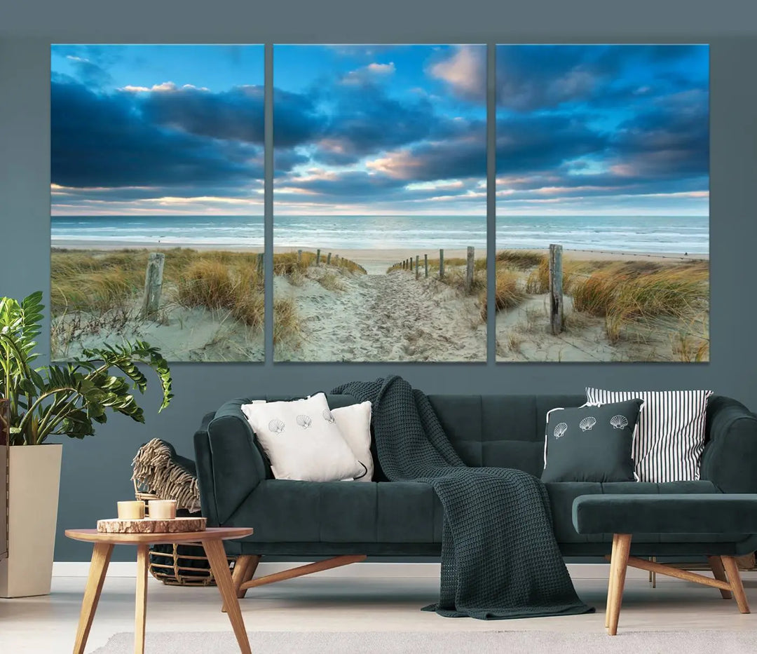 The "Beach Ocean Sun Sand Wall Art Canvas Print" is a triptych showcasing a beach path with grass leading to the ocean under a dramatic cloudy sky. This museum-quality canvas includes a UV-protective coating for longevity and vibrancy, and it comes ready to hang for effortless elegance.