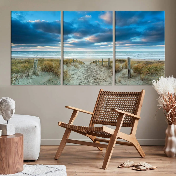 The "Beach Ocean Sun Sand Wall Art Canvas Print" is a triptych showcasing a beach path with grass leading to the ocean under a dramatic cloudy sky. This museum-quality canvas includes a UV-protective coating for longevity and vibrancy, and it comes ready to hang for effortless elegance.