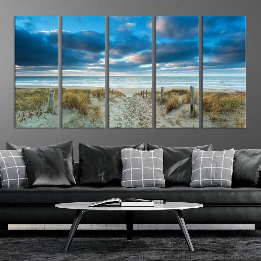 The "Beach Ocean Sun Sand Wall Art Canvas Print" is a triptych showcasing a beach path with grass leading to the ocean under a dramatic cloudy sky. This museum-quality canvas includes a UV-protective coating for longevity and vibrancy, and it comes ready to hang for effortless elegance.