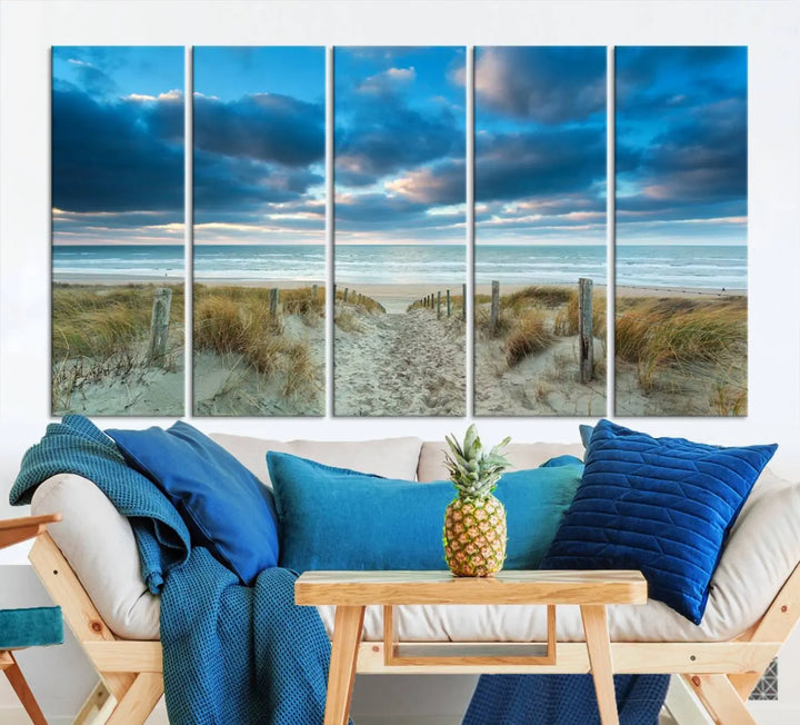 The "Beach Ocean Sun Sand Wall Art Canvas Print" is a triptych showcasing a beach path with grass leading to the ocean under a dramatic cloudy sky. This museum-quality canvas includes a UV-protective coating for longevity and vibrancy, and it comes ready to hang for effortless elegance.