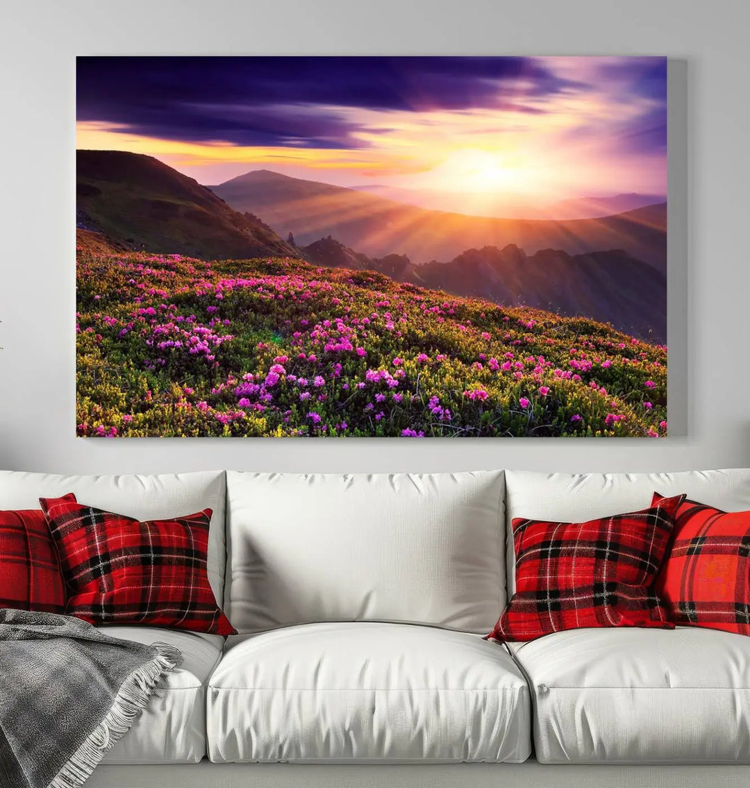 A living room showcases the Beautiful Mountain Sunset Landscape with Purple Flowers Canvas Wall Art Print, featuring a triptych of a vibrant sunset over mountains and blooming flowers, vividly rendered on museum-quality canvas with UV-protective coating.