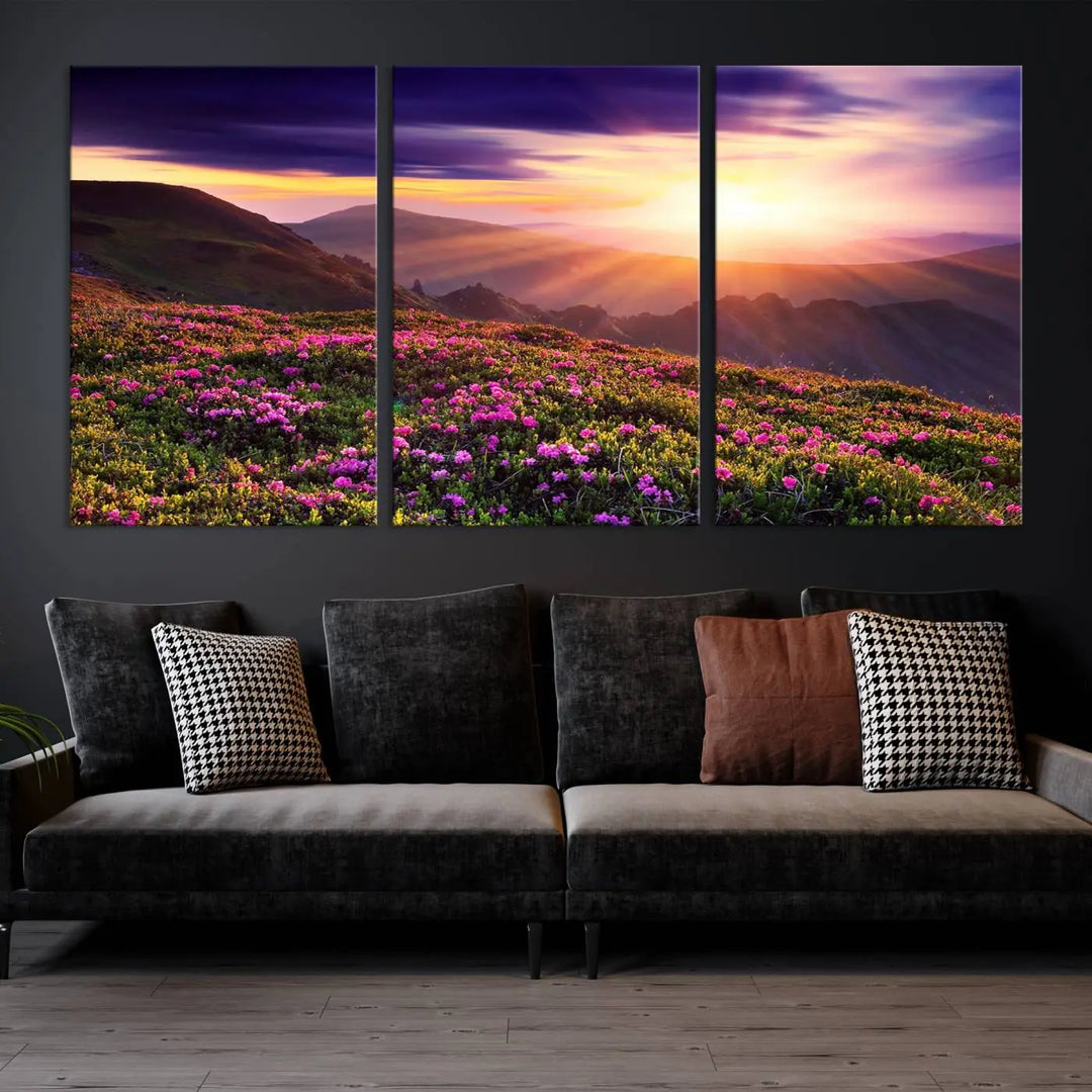 A living room showcases the Beautiful Mountain Sunset Landscape with Purple Flowers Canvas Wall Art Print, featuring a triptych of a vibrant sunset over mountains and blooming flowers, vividly rendered on museum-quality canvas with UV-protective coating.