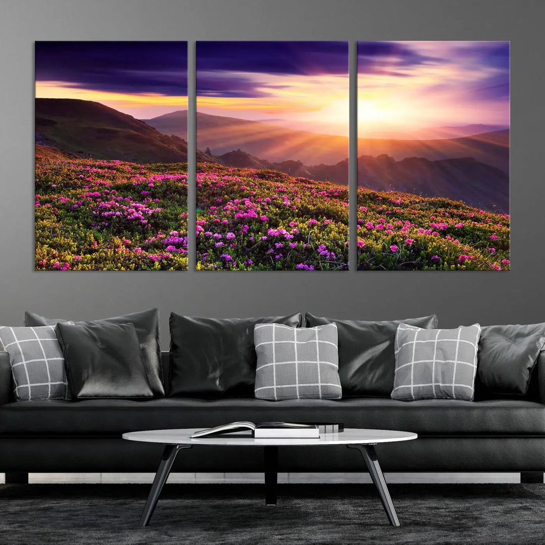 A living room showcases the Beautiful Mountain Sunset Landscape with Purple Flowers Canvas Wall Art Print, featuring a triptych of a vibrant sunset over mountains and blooming flowers, vividly rendered on museum-quality canvas with UV-protective coating.