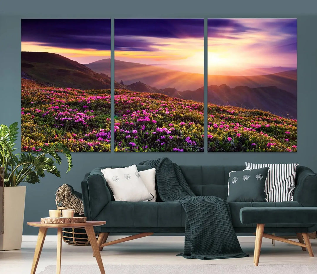 A living room showcases the Beautiful Mountain Sunset Landscape with Purple Flowers Canvas Wall Art Print, featuring a triptych of a vibrant sunset over mountains and blooming flowers, vividly rendered on museum-quality canvas with UV-protective coating.